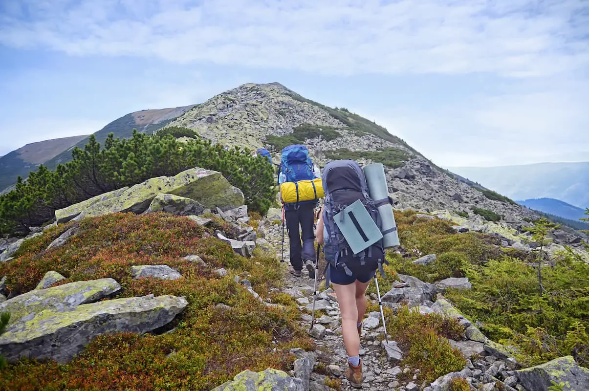 Young people hiking up a mountain with 30+ pound backpacks on.