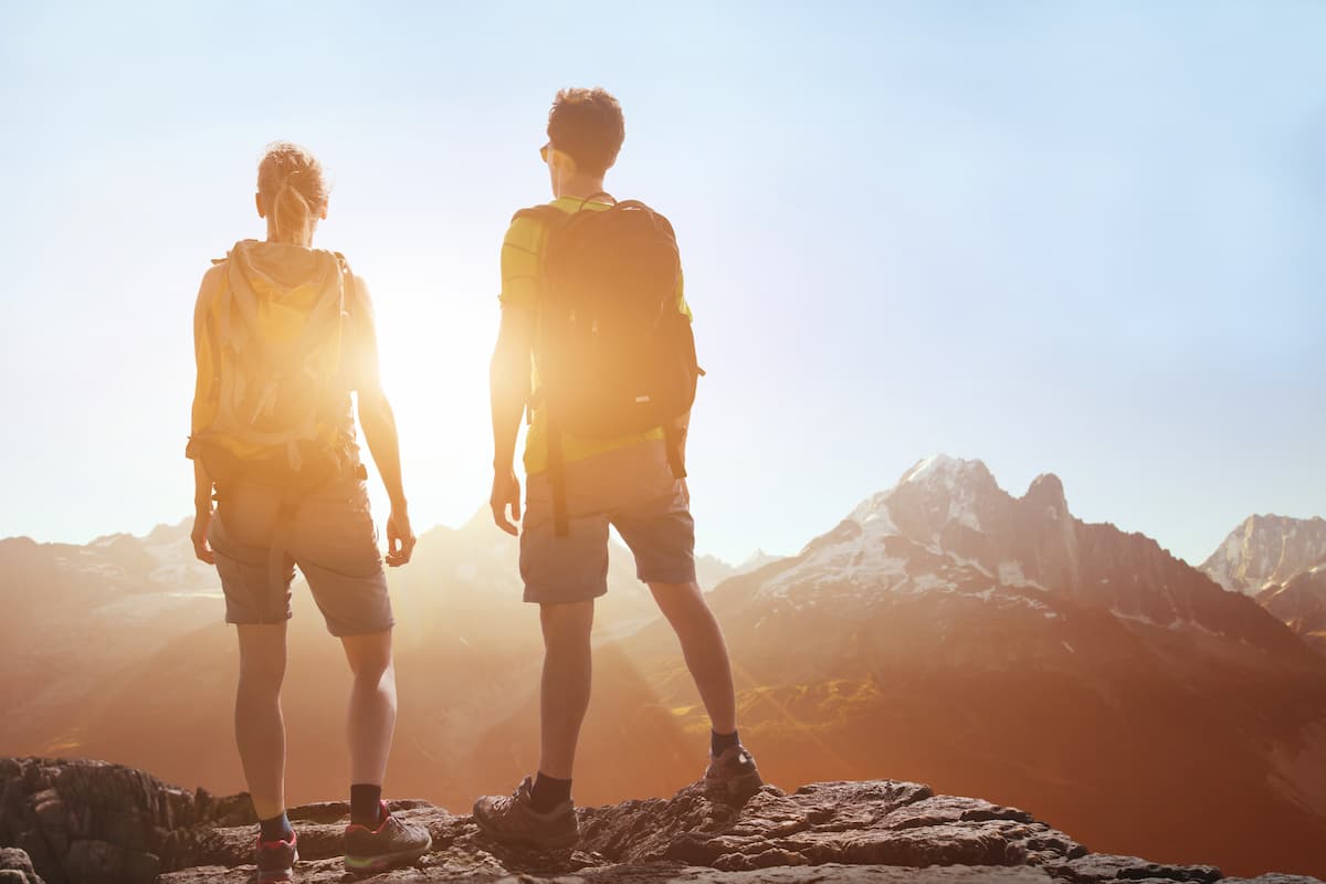 People traveling, hiking in mountains, couple of hikers looking at panoramic landscape view, summer trekking